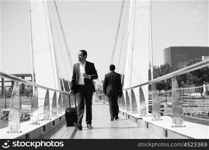 african businessman walking across modern bridge