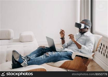 African businessman wearing VR glasses interacting with 3d objects in augmented virtual reality. Black guy using modern gadget for working in cyberspace sitting in armchair at laptop. Future high tech. African businessman in VR glasses interact with virtual reality sit in armchair at laptop. High tech