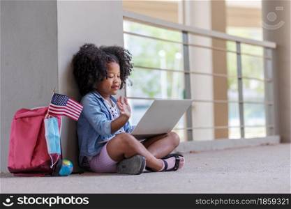 African children curly hair sitting under building and using computer portable information device talking with friend in new normal style.Social distancing concept.