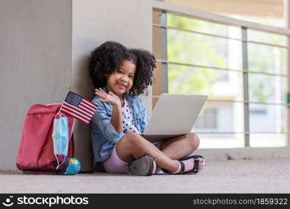 African children curly hair sitting under building and using computer portable information device talking with friend in new normal style.Social distancing concept.