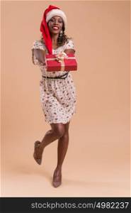 African Christmas woman wearing Santa Claus hat holding gift. Full length portrait