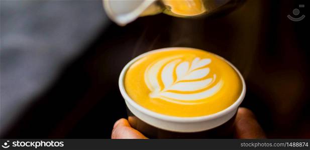 African Coffee Barista pouring a leaf shape with milk foam in a take away cup