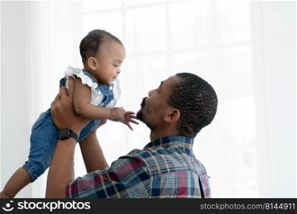 African father with beard carrying his newborn baby girl up in the air and playing together with happy face at home. Relationship of dad and little daughter. White background