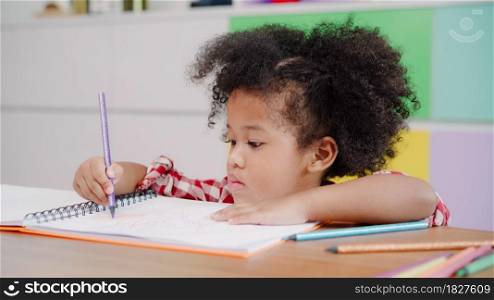 African kids drawing and do homework in classroom, young girl happy funny study and play painting on paper at elementary school. Kid drawing and painting at school concept.
