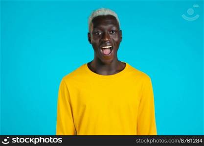 African man depicts amazement, shows WOW delight face effect. Surprised excited happy guy. Handsome male shocked model on blue background. African man depicts amazement, shows WOW delight face effect. Surprised excited happy guy. Handsome male shocked model on blue background.