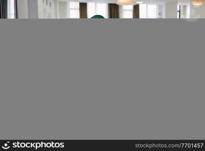 african muslim business woman wearing a green hijab drinking tea while working on laptop computer in relaxation area at modern open plan startup office. Diversity, multiracial concept