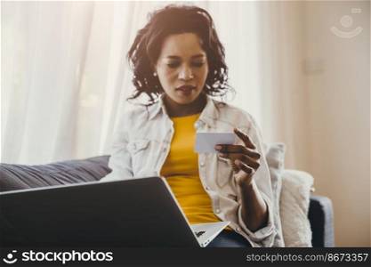 African or Black people hand and looking at name card or credit card with laptop computer search at home or online shopping concept.