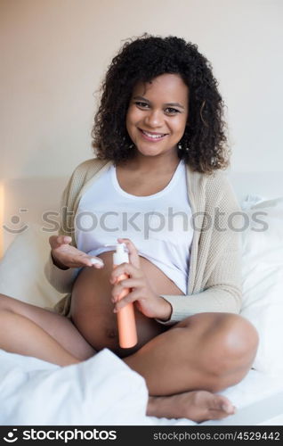 African Pregnant woman moisturizing her belly