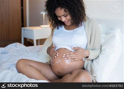 African Pregnant woman moisturizing her belly