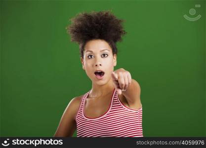 African woman astonished with something and pointing, over a green background
