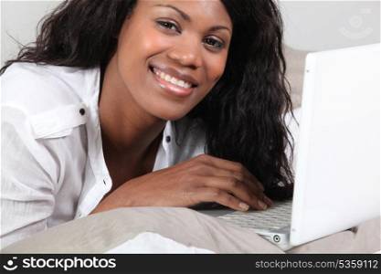 African woman lying and having fun with her laptop