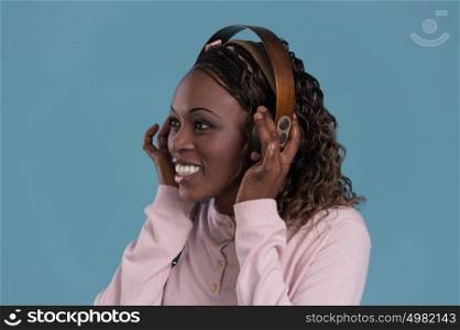 African woman with headphones listening music. Music teenager girl dancing against blue background