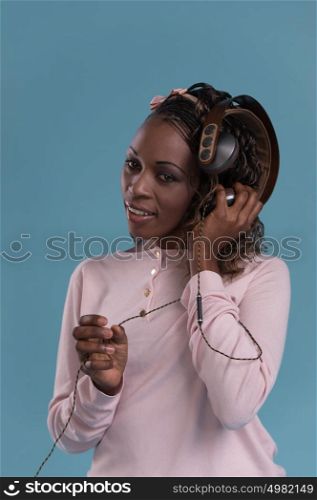 African woman with headphones listening music. Music teenager girl dancing against blue background