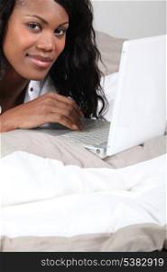 African woman with laptop in bed