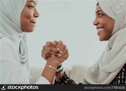 African women arm wrestling conflict concept, disagreement, and confrontation wearing traditional Islamic hijab clothes. Selective focus. High-quality photo. African woman arm wrestling conflict concept, disagreement and confrontation wearing traditional islamic hijab clothes. Selective focus