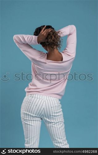 African young woman posing against blue background. Photo from behind