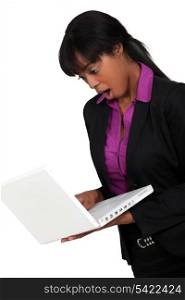 Afro-American businesswoman holding her laptop and looking very surprised