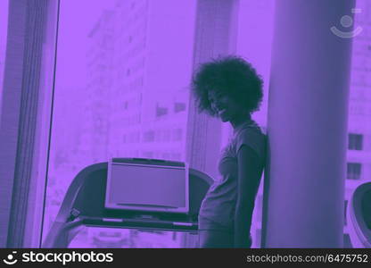 afro american woman running on a treadmill. afro american woman running on a treadmill at the gym while listening music on earphones duo tone filter