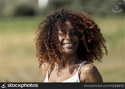 Afro american woman with white dress sitting on grass in a park in sunny day