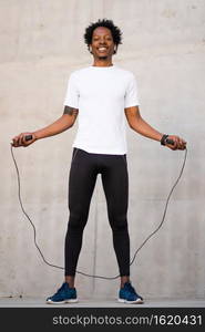 Afro athletic man doing exercise and jumping the rope outdoors. Sport and healthy lifestyle concept.