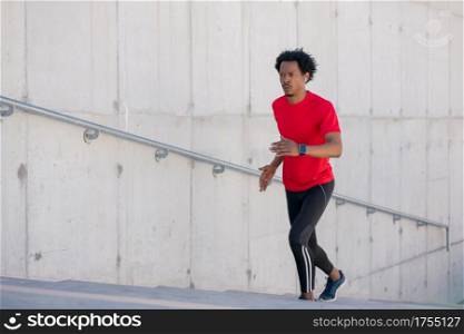 Afro athletic man doing exercise and running up stairs outdoors. Sport and healthy lifestyle concept.