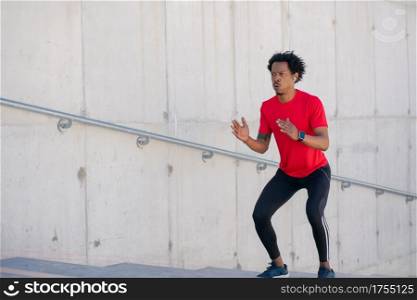Afro athletic man doing exercise outdoors at stairs. Sport and healthy lifestyle.