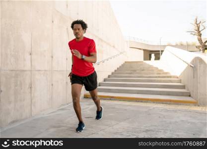 Afro athletic man running and doing exercise outdoors on the street. Sport and healthy lifestyle concept.