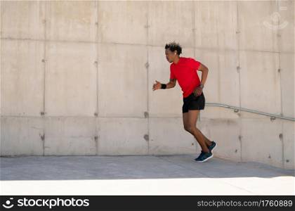 Afro athletic man running and doing exercise outdoors on the street. Sport and healthy lifestyle concept.