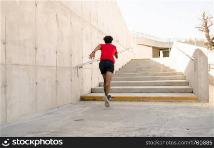 Afro athletic man running and doing exercise outdoors. Sport and healthy lifestyle concept.
