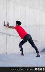 Afro athletic man stretching and warming up before exercise outdoors. Sport and healthy lifestyle.