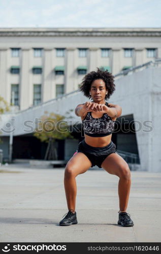 Afro athletic woman doing exercise outdoors on the street. Sport and healthy lifestyle.