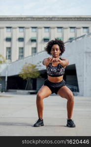 Afro athletic woman doing exercise outdoors on the street. Sport and healthy lifestyle.