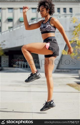 Afro athletic woman doing exercise outdoors on the street. Sport and healthy lifestyle concept.