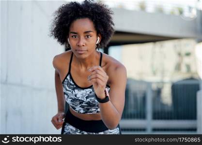 Afro athletic woman running and doing exercise outdoors. Sport and healthy lifestyle concept.