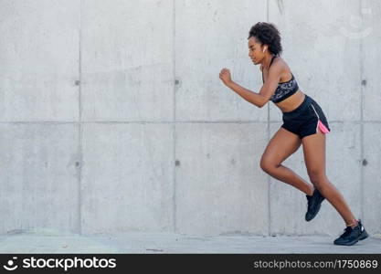 Afro athletic woman running and doing exercise outdoors. Sport and healthy lifestyle concept.