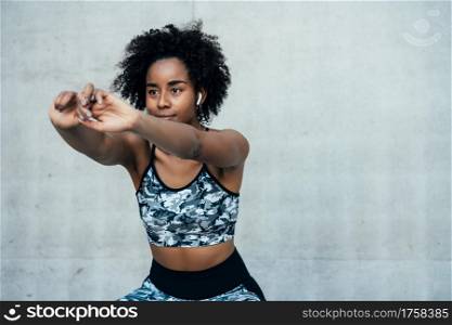 Afro athletic woman stretching and warming up before exercise outdoors. Sport and healthy lifestyle.