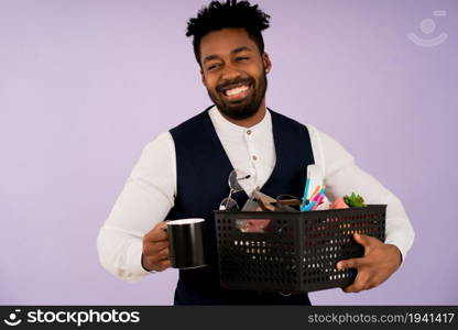 Afro businessman holding a box with personal items for the office while standing against an isolated background. Business concept.