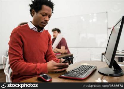 Afro businessman using his mobile phone and working at his workplace. Business concept.
