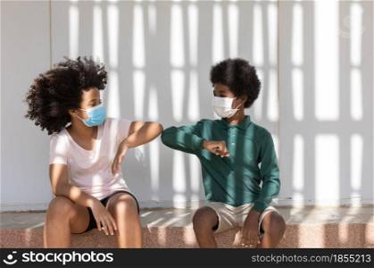 Afro children curly hair with protective masks together in under the shadowed eaves of building, People are wearing protective face masks to prevent coronavirus spread.