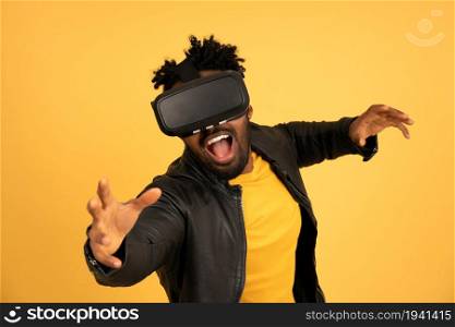 Afro man playing video games with VR glasses while standing over an isolated background. Technology concept.