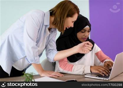 ?afro muslim  woman  wearing a hijab sits smiling in her home office and using laptop for online meeting
