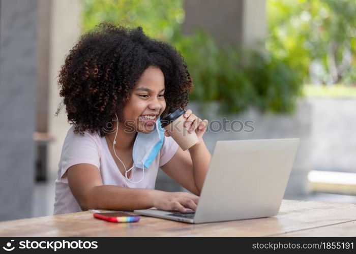 Afro teenage girls using laptop to learning online at home and drinking coffee sitting under building