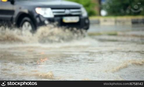 After a hard rain, people are driving their cars in the flood water