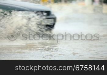 After a hard rain, people are driving their cars in the flood water