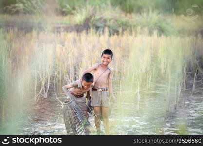 After class, little boys in rural Thailand like catching fish in the wetlands surrounding the rice fields to bring home to cook.