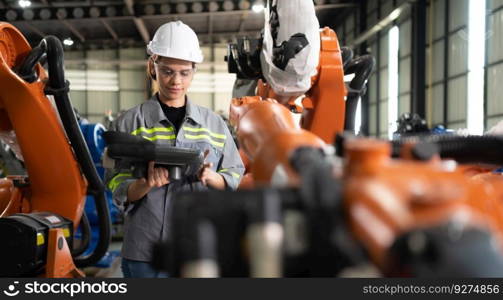 After installing a program on the robotic arm, a female engineer with a robotic arm controller performs a test run.