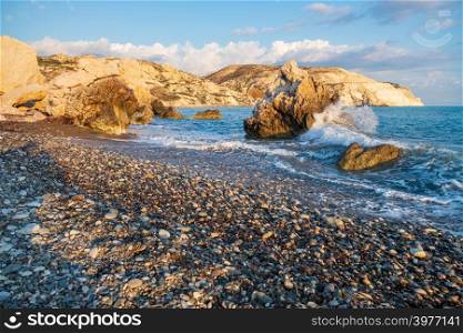 Afternoon view of breaking waves at the pebbly beach around Petra tou Romiou, in Paphos, Cyprus. It is considered to be Aphrodite&rsquo;s birthplace in Greek mythology.