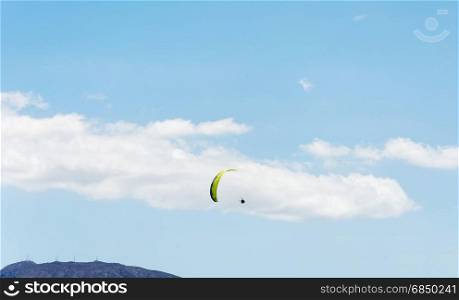 Against the background of mountains and blue sky with clouds athletes are planning a paraglider