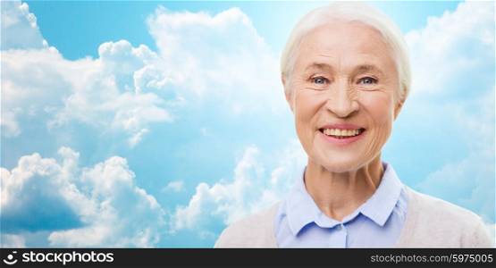 age and people concept - happy smiling senior woman face over blue sky and clouds background. happy senior woman face over blue sky and clouds