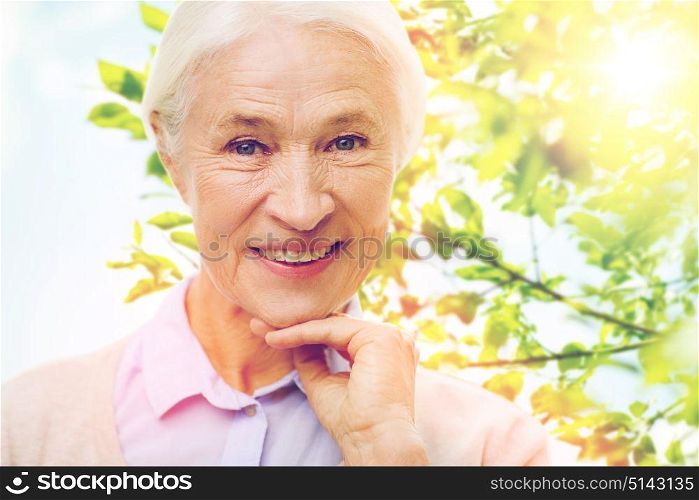 age and people concept - happy smiling senior woman face over green natural background. happy senior woman over green natural background
